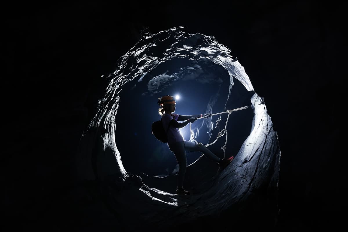 The visitor holds onto a rope to pose inside the giant circular rock chamber.